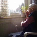 Elderly woman looking out of the window: