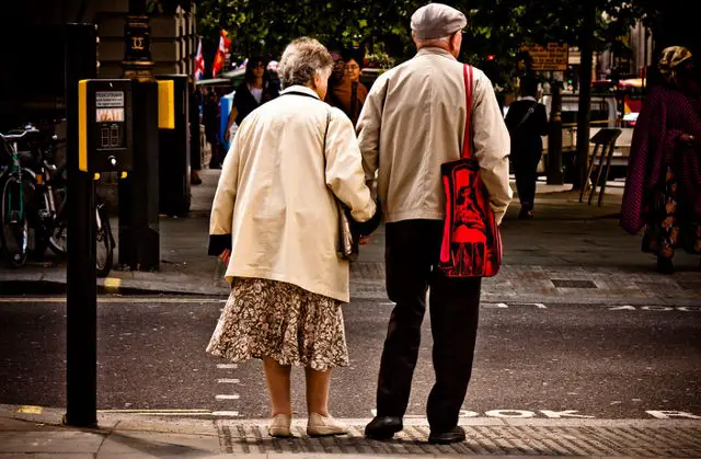 Elderly people holding hands crossing the road