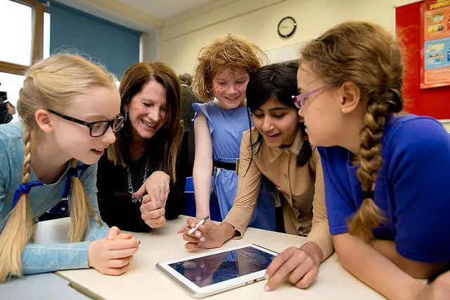 pupils and teachers in school around an ipad 