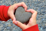 childs hand around a love heart stone