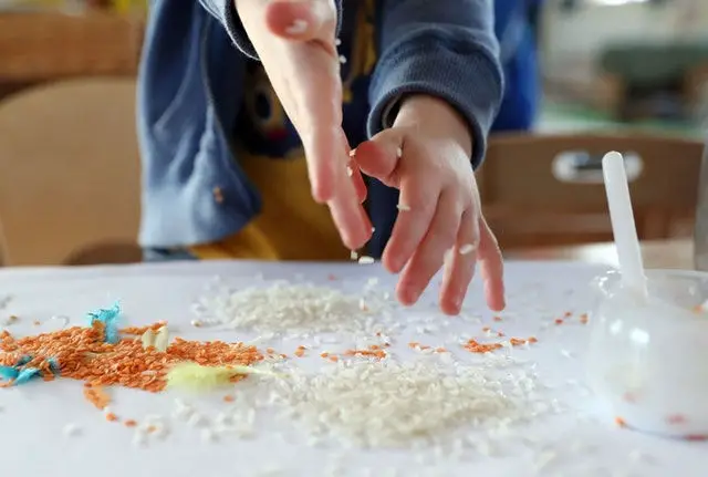 young child making art with lentils