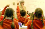 Children in classroom with hands up