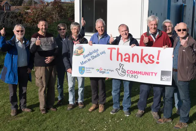 Men in sheds with banner saying thank you