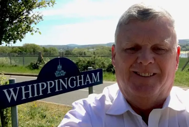 Cllr Michael Paler standing next to Whippingham sign