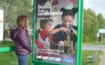 Girl looking at Guides advert in bus shelter