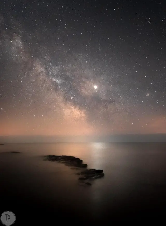 The Milky Way and Jupiter reflected in the sea by Theo Vickers