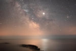milky way and jupiter reflected on the calm sea