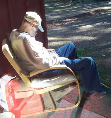 Old man sleeping in chair in garden
