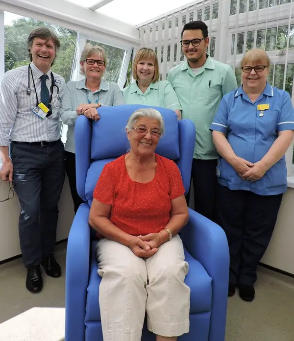 Mrs Sorensen seated in the new therapy chair with rheumatology staff