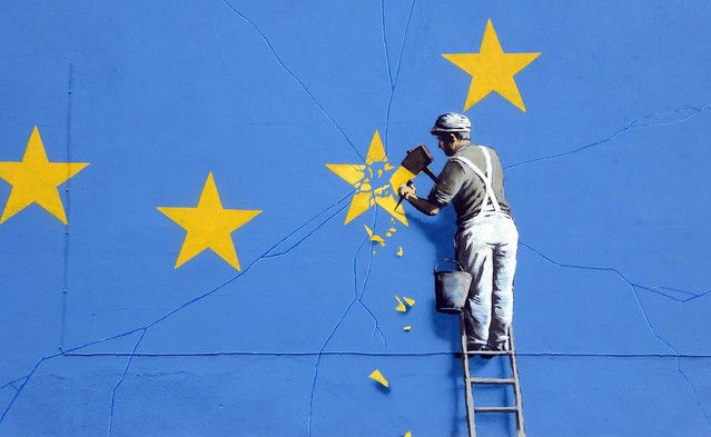 banksy mural of workman chipping a star from the european flag