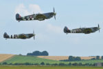 three spitfires flying over countryside