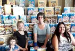 children and councillor in front of a wall of cereal boxes