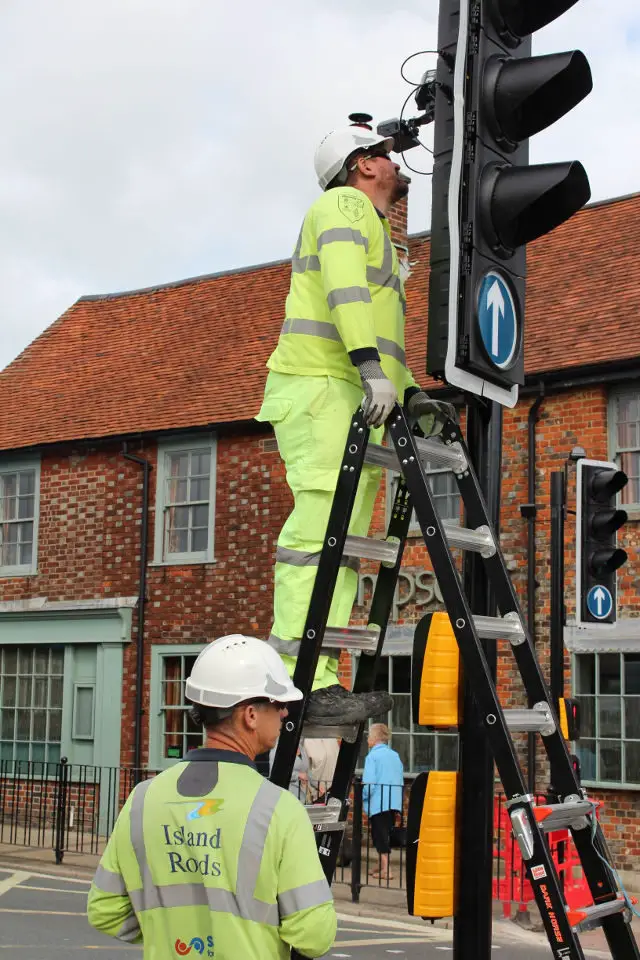 Staff attending to the traffic lights on a ladder