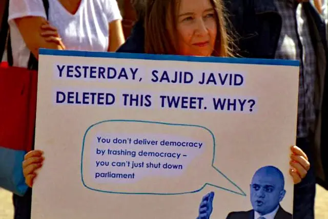 Placardshowing deleted tweet by Savid Javid