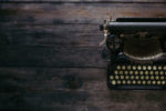 antique typewriter on dark wood table on unsplash by Patrick Fore