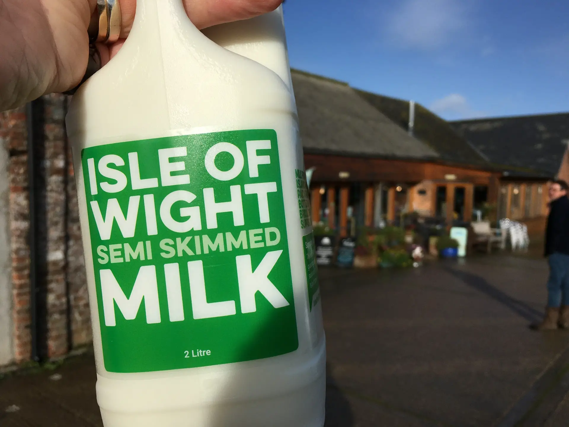 Isle of Wight Milk processing plant at Briddlesford Dairy Farm - bottle of milk being held up outside the farm buildings