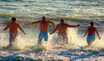 men running into the sea