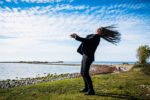 woman standing by the seawith hair blowing in the strong wind