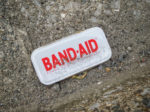 band aid tin lid on pavement