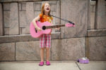 little girl playing guitar on the street