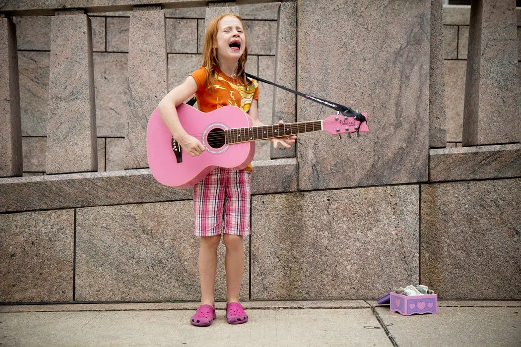 little girl playing guitar on the street