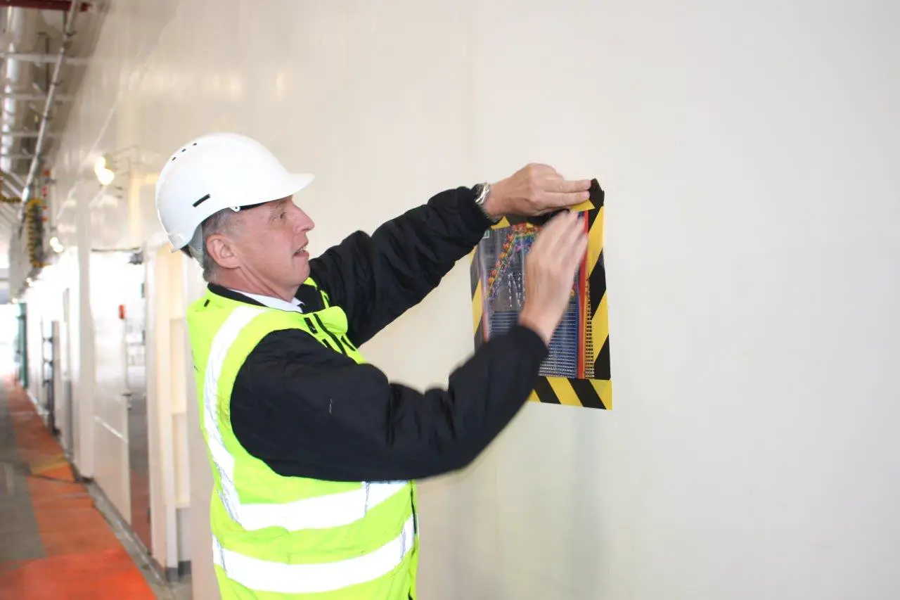 Dave Grace fixing children's paintings to the car deck on Wightlink's Victoria of Wight