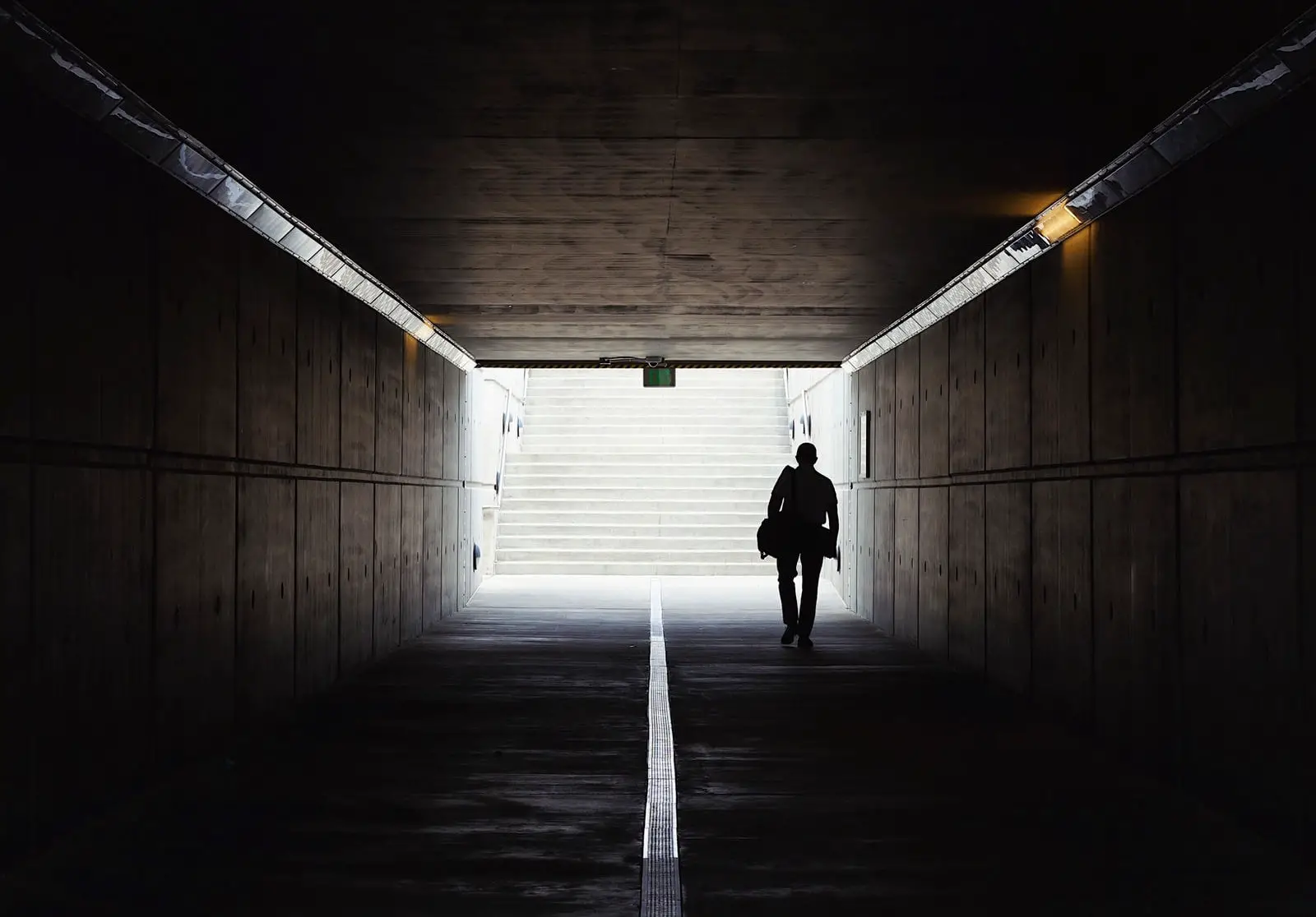 man walking out of tunnel by