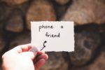 person holding a card which says "phone a friend"