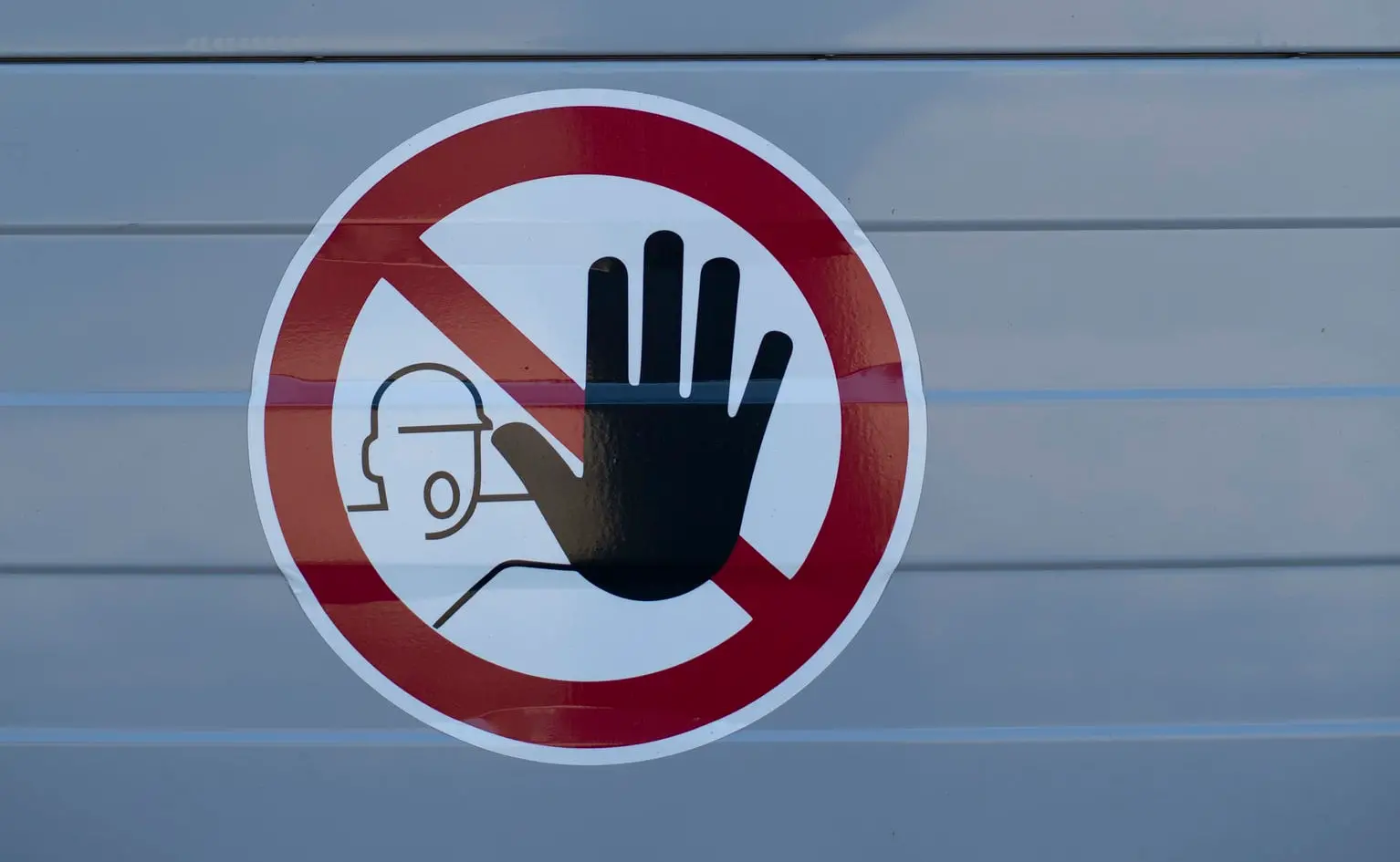 sticker on wall showing man with hand out signalling stop by Markus Spiske