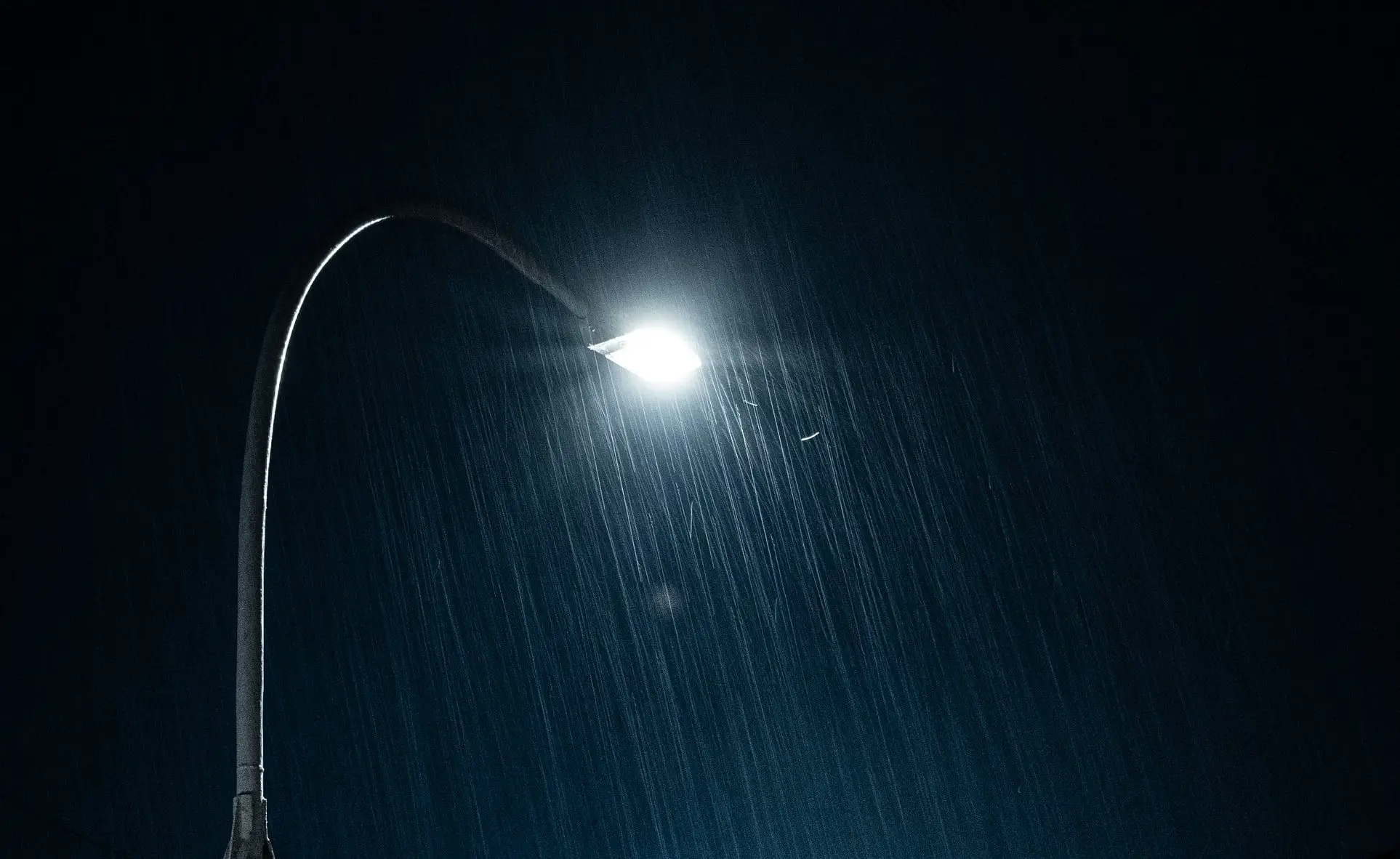 Streetlamp lighting rain in night sky