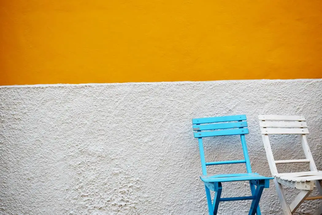 Two fold up chairs in front of a white and orange painted wall