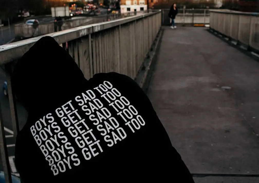 man in hoodie with Boys Get Sad Too written on back of it