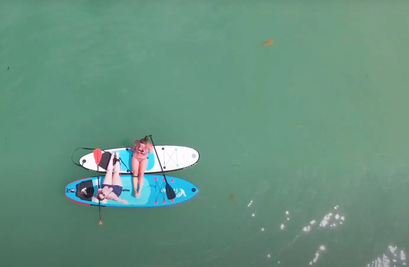 Two women resting on paddle-boards -shot from above