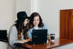 two young women looking at computer