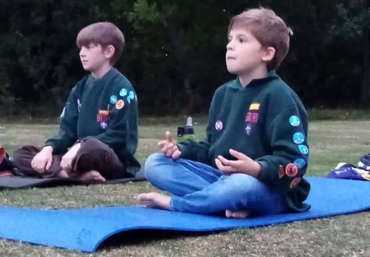 Two scouts sitting on the ground cross legged