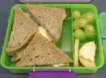 packed lunch box with a sandwich, grapes and biscuits