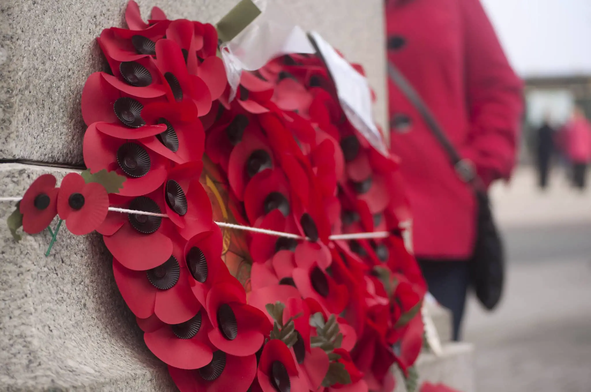 poppy wreaths and woman standing in the background with red coat and black buttons