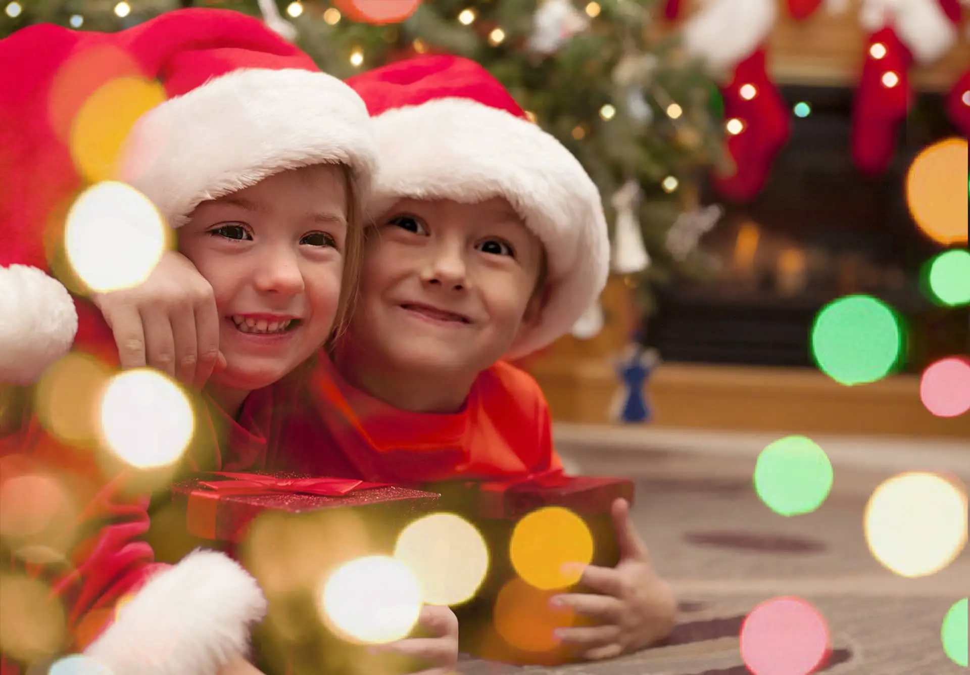Two children with Xmas hats and presents