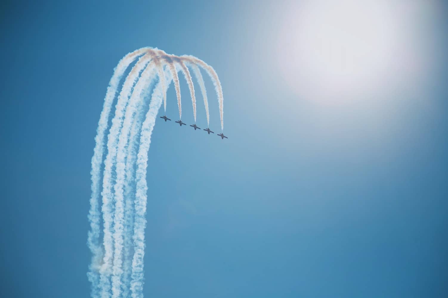 five planes doing aerobatics in the sky by Takahiro Sakamoto