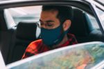 man wearing a mask sat in back of a car