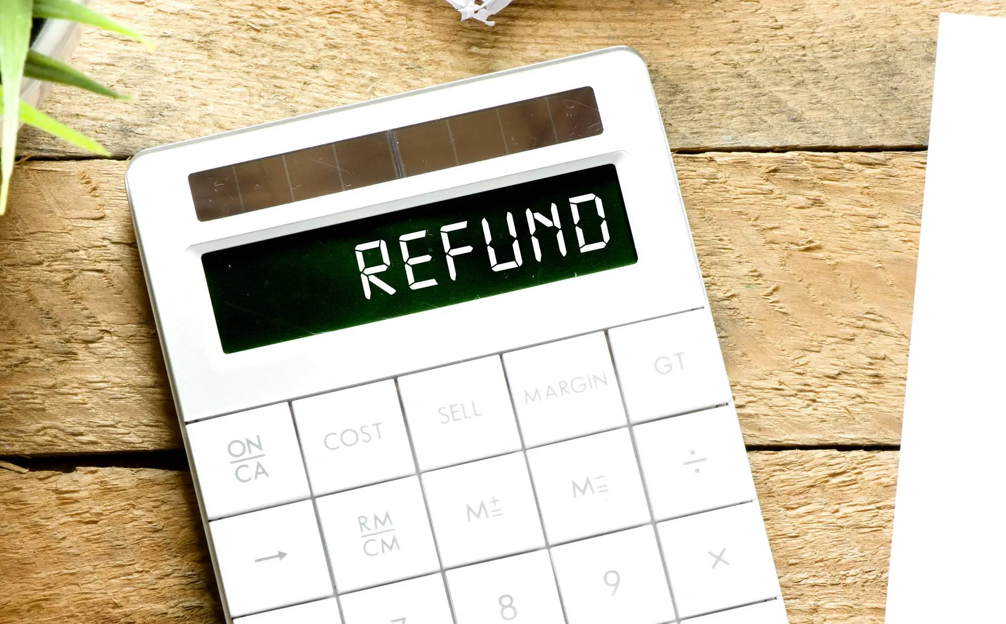 refund spelled out on calculator placed on desk with plant next to it