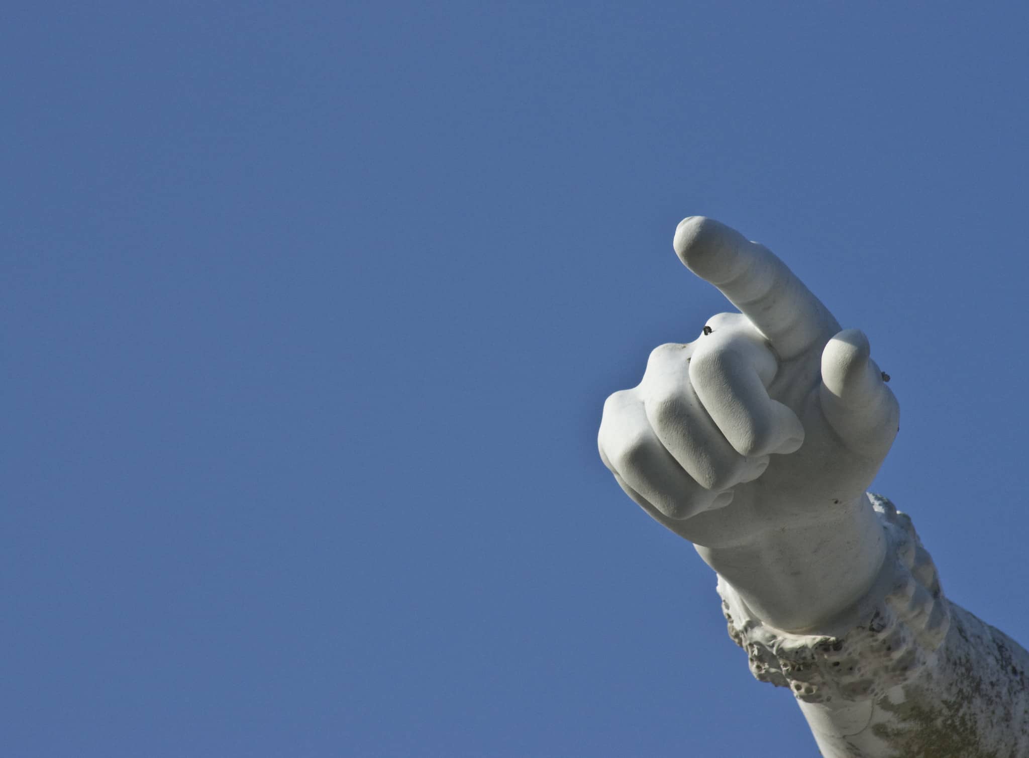 statue of finger pointing with blue sky in background