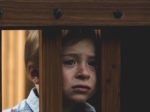 unhappy child leaning on wooden fence