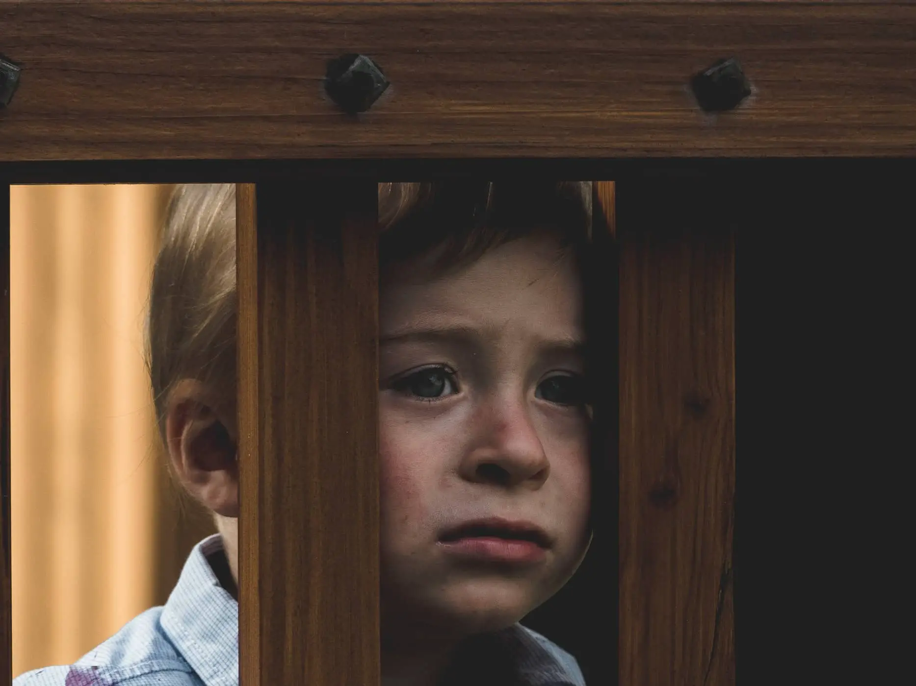 unhappy child leaning on wooden fence