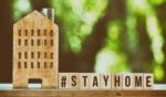 wooden house sitting on window sill with message stay home next to it