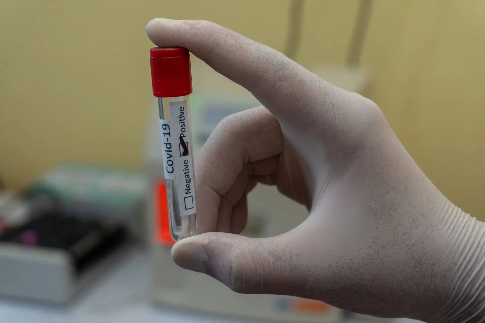 person with gloves holding a vial with positive Covid-19 test