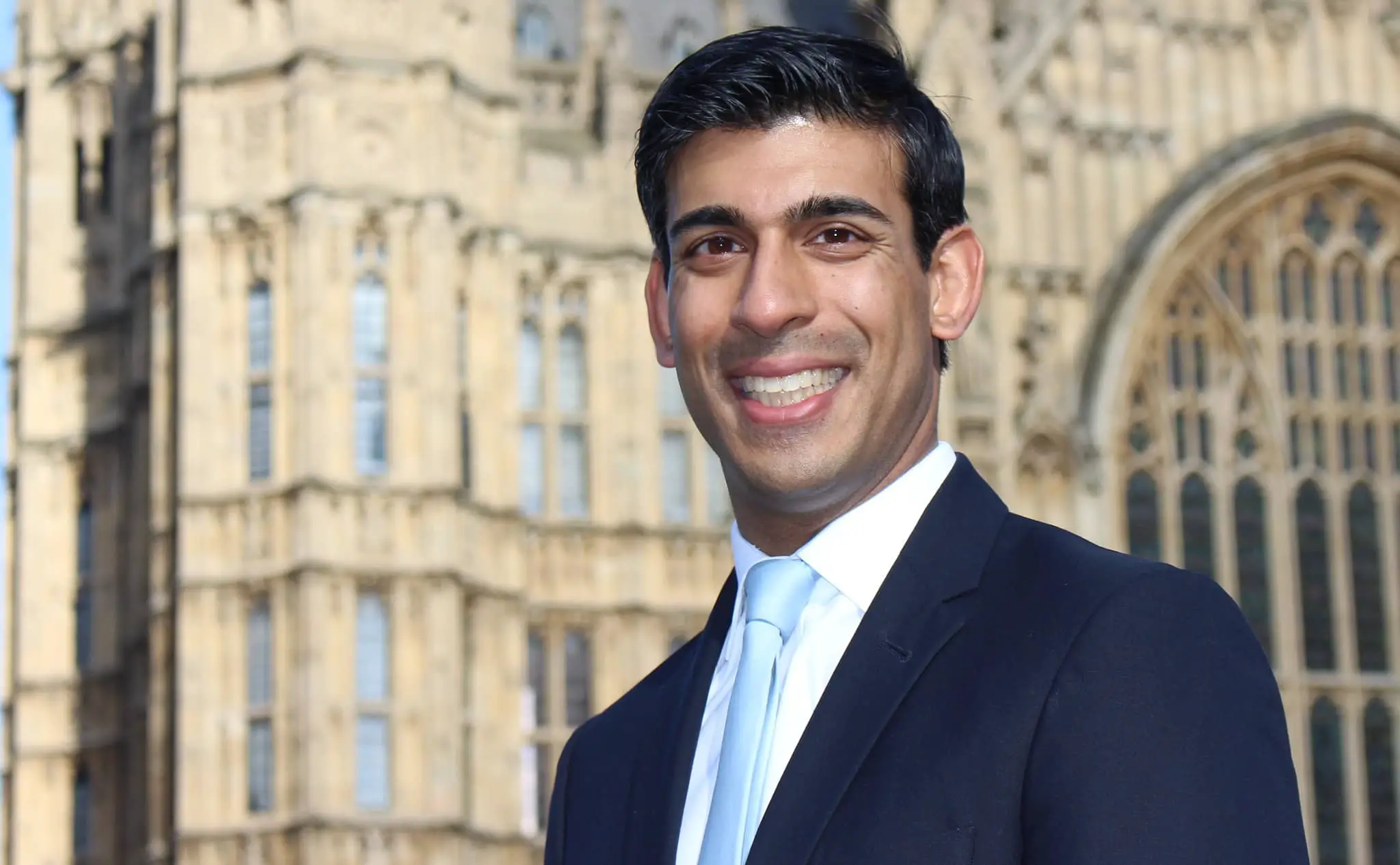 Rishi Sunak standing in front of Houses of Parliament