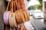 Bags hanging outside shop with cars driving past - blurred