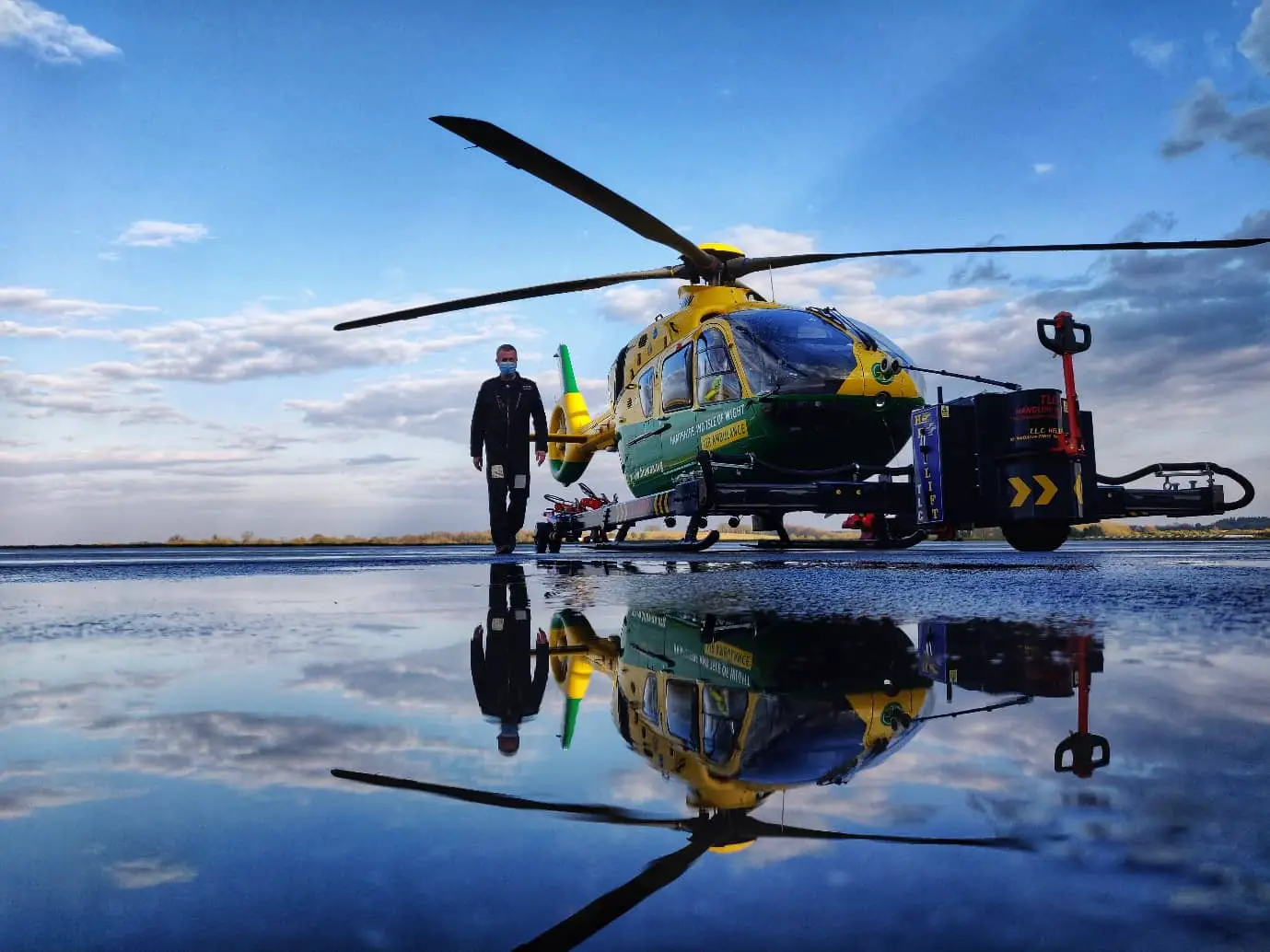 Man walking by the air ambulance with reflection in puddle
