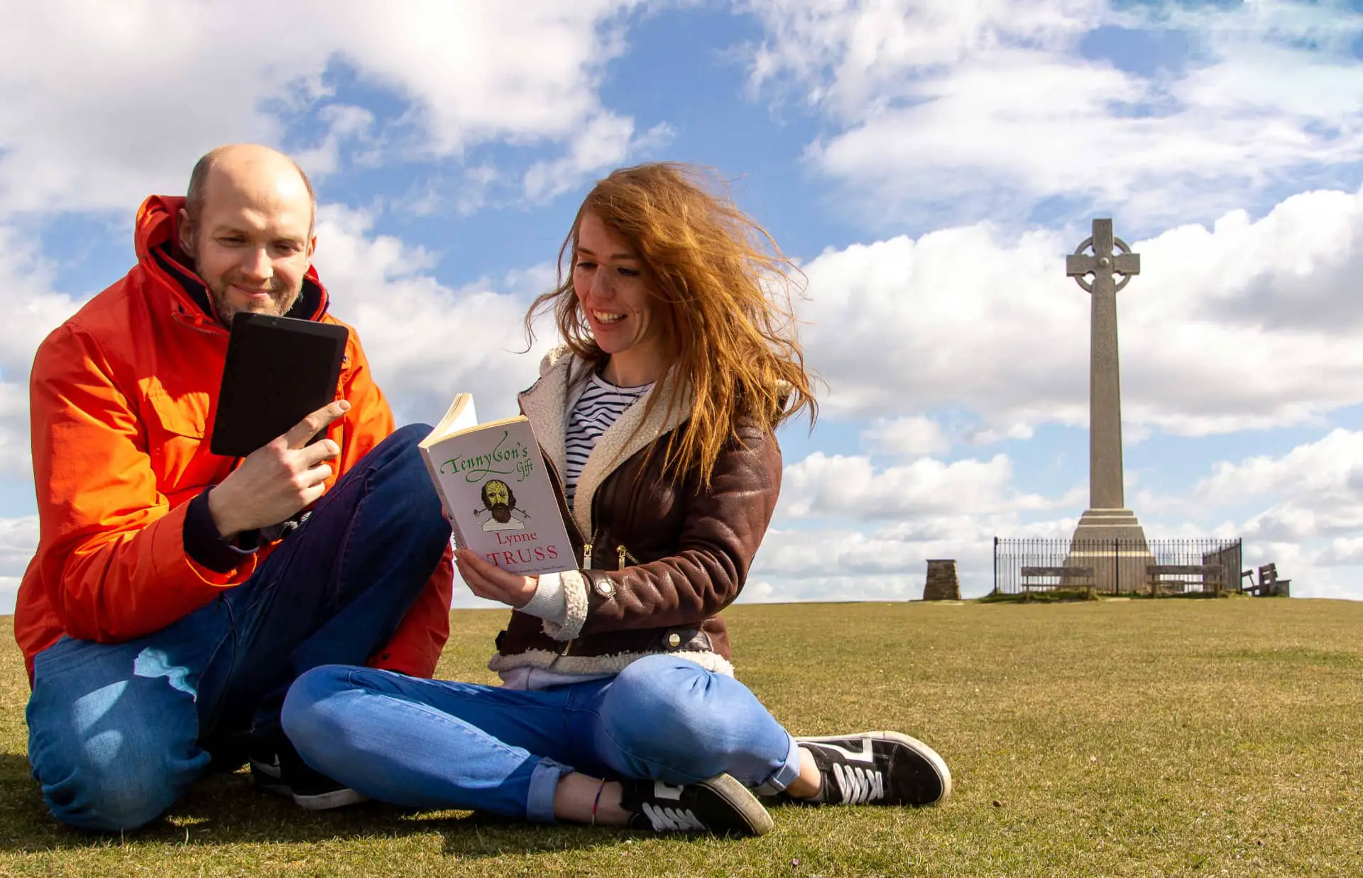 Two people by the Tennyson Monument one reading a book the other with a tablet